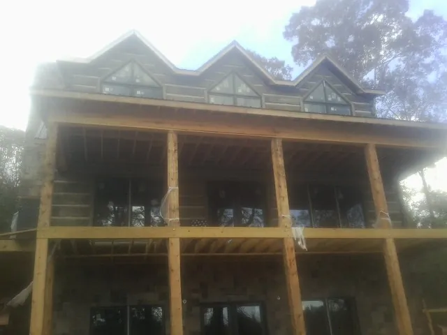 Dormers and porch framing on a large log home under construction — Roof Coating work by our crew in Iron Station