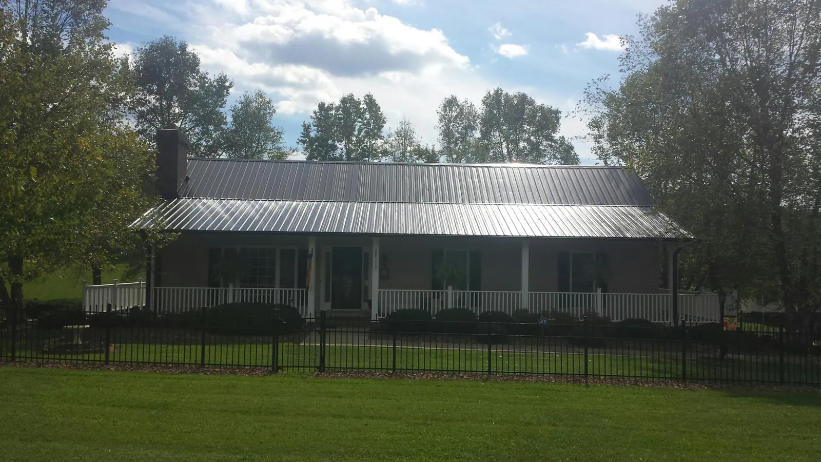 Gray metal roof on a brick ranch with a full width front porch — Gutter Guard Installation work by our crew in Iron Station