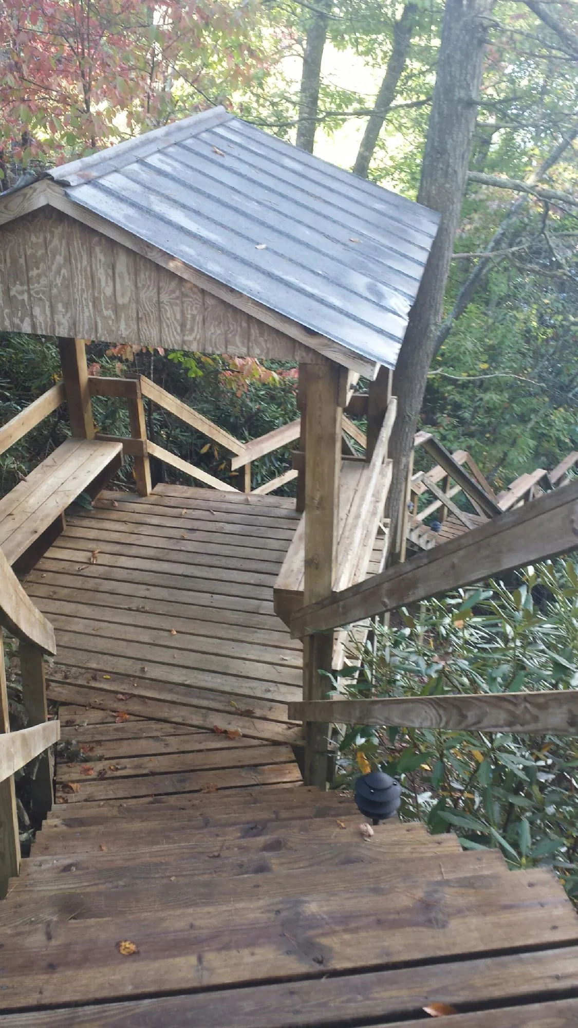 Metal roofed shelter over wooden steps on a wooded walkway — Skylight Repair & Installation work by our crew in Iron Station