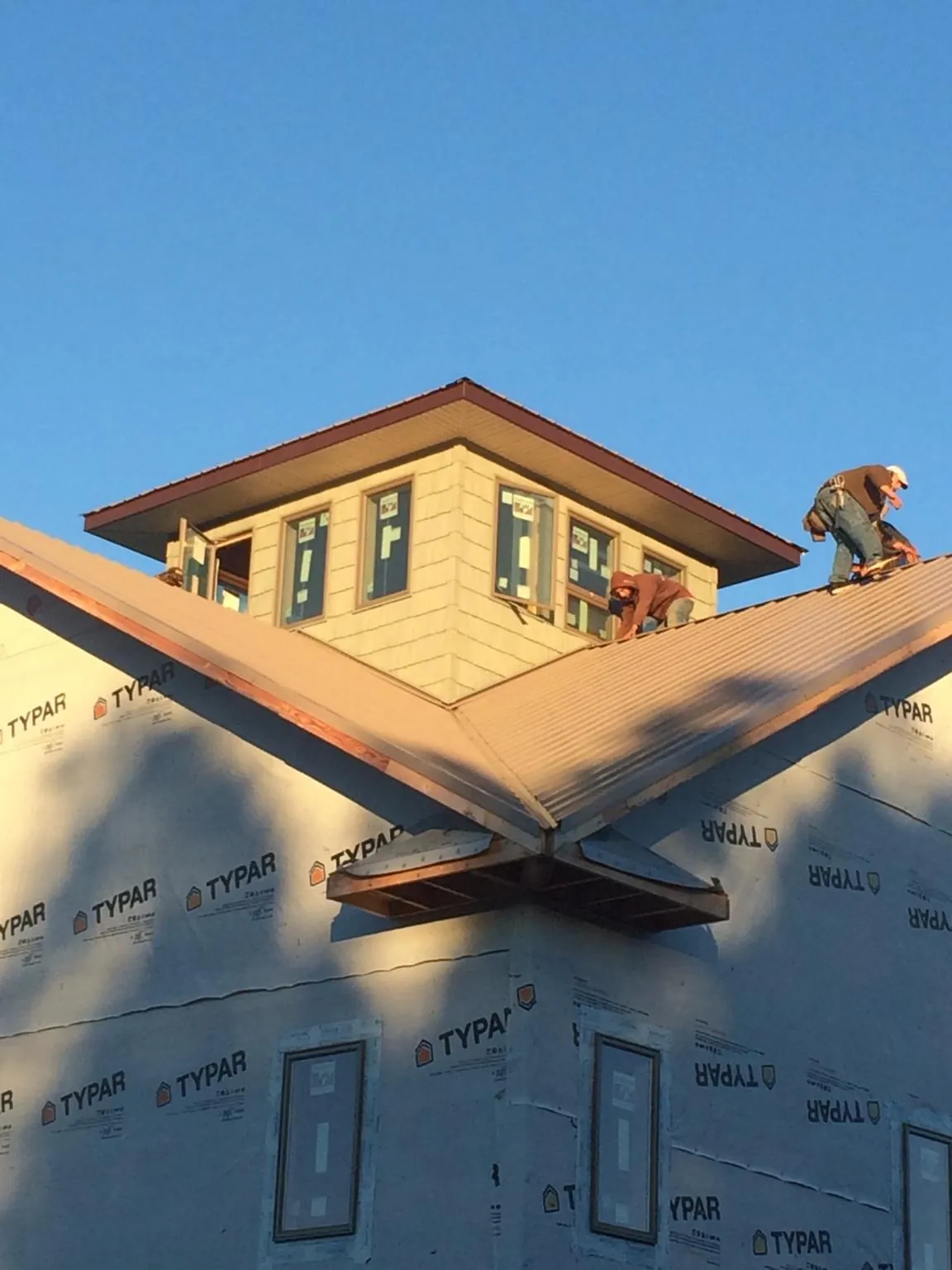 Roofers working around a rooftop cupola on a new metal roof at sunset — Roof Waterproofing in Iron Station by Roofing Brothers